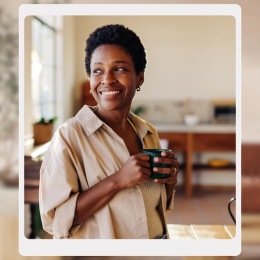 a woman smiling and holding a cup of coffee